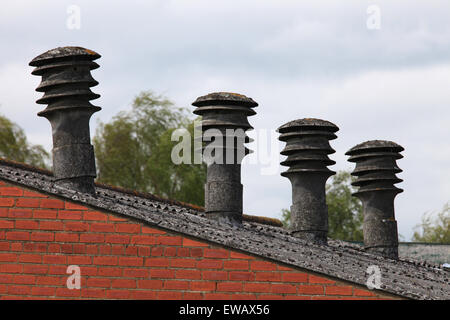 Ancienne usine d'amiante avec des pots de cheminée/flues visibles au-dessus de la ligne du toit, toit de l'amiante et mur de brique rouge très cher travaille Banque D'Images