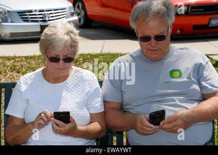 Couple côte à côte des messages sur leurs téléphones portables Banque D'Images