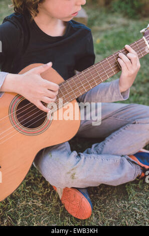 Petite blonde Garçon jouant de la guitare espagnole à l'extérieur. L'identité de l'enfant est caché. Banque D'Images