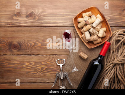 Bouteille de vin rouge, verre à vin, bol avec bouchons et tire-bouchon. Vue de dessus sur fond de table en bois rustique Banque D'Images