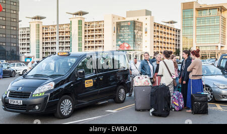 Les passagers avec bagages debout à une borne de taxi devant le hall des arrivées de l'aéroport de Birmingham, England, UK Banque D'Images