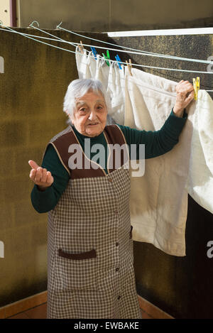 Femme âgée traînant le lave-linge sur la terrasse de sa chambre. Banque D'Images