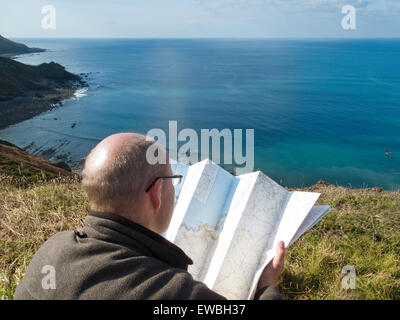 Walker se repose et lit la carte sur falaise donnant sur South West Coast Path à Cornwall Banque D'Images