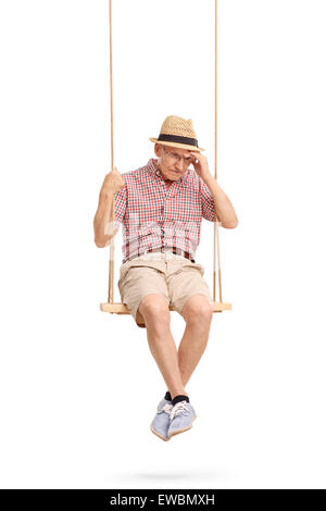 Shot vertical d'un déprimé senior man sitting on a swing et de se rappeler quelque chose d'isolé sur fond blanc Banque D'Images