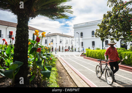 Homme marchant avec des fleurs par Parque Caldras, Popayan, Colombie. Banque D'Images