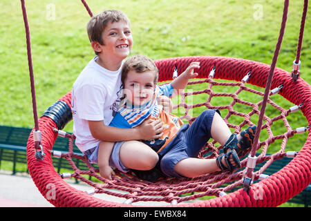 Deux enfants sur l'aire de s'amuser sur swing tour Banque D'Images