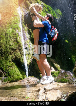 Image romantique ou une photo, l'homme leva femme à côté de forest waterfall. Moment d'amour de jeune couple dans la nature. Les hommes et les hav Banque D'Images