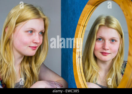 Européenne blonde woman looking in mirror Banque D'Images