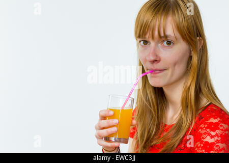 Redhead caucasian woman drinking orange juice avec paille isolé sur fond blanc Banque D'Images