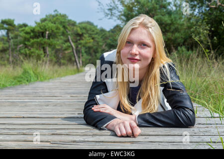 Blonde woman lying on wooden sentier dans la nature Banque D'Images