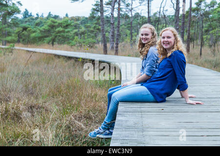 Deux sœurs adolescentes assis sur un sentier en forêt Banque D'Images