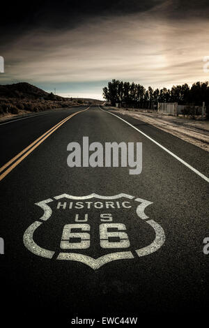 L'image classique de l'historique Route 66 sign painted sur l'autoroute. Les nuages sombres et Moody, ciel voilé sunshine Banque D'Images