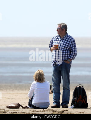 L'homme jouissant d'une pinte de bière dans un verre sur la plage à Weston super Mare, Juin 2015 Banque D'Images