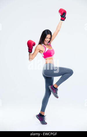 Portrait d'une femme de remise en forme dans des gants de boxe célèbre son succès sur un fond gris Banque D'Images