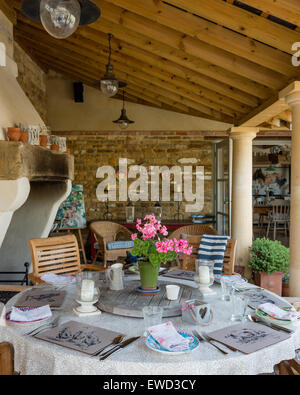 Table ronde et chaises en bois dans jardin prix / loggia avec piliers en grès et de poutres au plafond en pente Banque D'Images