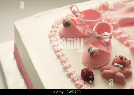 Détails d'une décoration de gâteau d'anniversaire pour petite fille. Chaussures et robe faite de sucre rose. Banque D'Images