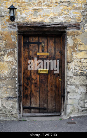 Vieille porte en bois dans une maison en pierre de Cotswold dans les Cotswolds, en Angleterre, UK. Banque D'Images