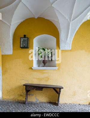 Banc en bois contre le mur en pierre jaune dans l'entrée avec plafond voûté arch Banque D'Images