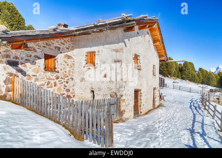 Chalet alpin entouré par une clôture dans la neige entre les sommets enneigés et les forêts de pins sur une journée ensoleillée en hiver Banque D'Images