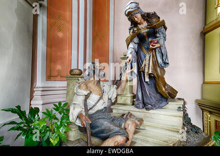 Bois sculpté statue de Saint Elizabeth donnant une pièce de monnaie avec sa main droite à la main gauche de mendiant comme geste de charité Banque D'Images