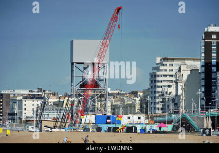 Brighton, UK. 24 Juin, 2015. Les gens s'assoient sur la plage de Brighton, tôt ce matin au beau temps par la construction de la nouvelle tour d'observation i360 qui est construite sur le front de mer en face de l'ancienne jetée Ouest le j360 est un 162 mètres (531 ft) tour d'observation en cours de construction sur le front de mer par l'entreprise hollandaise Hollandia Banque D'Images