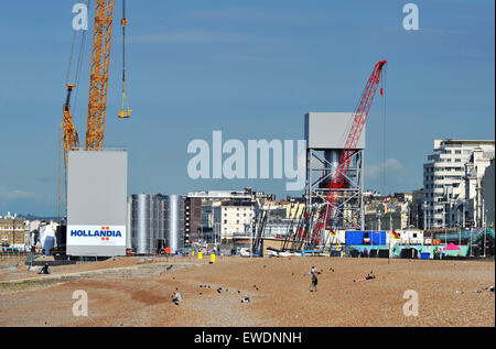 Brighton, UK. 24 Juin, 2015. Les gens s'assoient sur la plage de Brighton, tôt ce matin au beau temps par la construction de la nouvelle tour d'observation i360 qui est construite sur le front de mer en face de l'ancienne jetée Ouest le j360 est un 162 mètres (531 ft) tour d'observation en cours de construction sur le front de mer par l'entreprise hollandaise Hollandia Banque D'Images