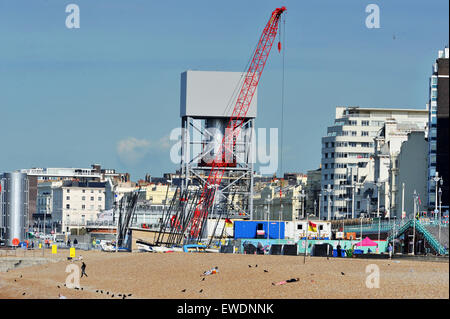 Brighton, UK. 24 Juin, 2015. Les gens s'assoient sur la plage de Brighton, tôt ce matin au beau temps par la construction de la nouvelle tour d'observation i360 qui est construite sur le front de mer en face de l'ancienne jetée Ouest le j360 est un 162 mètres (531 ft) tour d'observation en cours de construction sur le front de mer par l'entreprise hollandaise Hollandia Banque D'Images