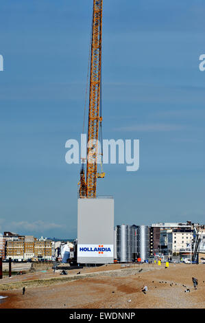 Brighton, UK. 24 Juin, 2015. Les gens s'assoient sur la plage de Brighton, tôt ce matin au beau temps par la construction de la nouvelle tour d'observation i360 qui est construite sur le front de mer en face de l'ancienne jetée Ouest le j360 est un 162 mètres (531 ft) tour d'observation en cours de construction sur le front de mer par l'entreprise hollandaise Hollandia Banque D'Images