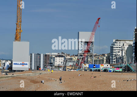 Brighton, UK. 24 Juin, 2015. Les gens s'assoient sur la plage de Brighton, tôt ce matin au beau temps par la construction de la nouvelle tour d'observation i360 qui est construite sur le front de mer en face de l'ancienne jetée Ouest le j360 est un 162 mètres (531 ft) tour d'observation en cours de construction sur le front de mer par l'entreprise hollandaise Hollandia Banque D'Images