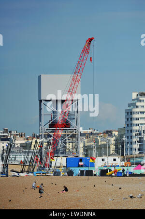 Brighton, UK. 24 Juin, 2015. Les gens s'assoient sur la plage de Brighton, tôt ce matin au beau temps par la construction de la nouvelle tour d'observation i360 qui est construite sur le front de mer en face de l'ancienne jetée Ouest le j360 est un 162 mètres (531 ft) tour d'observation en cours de construction sur le front de mer par l'entreprise hollandaise Hollandia Banque D'Images