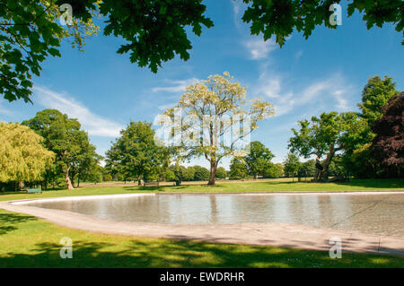 Nettoyer arborée Tettenhall pataugeoire par un beau jour d'été ensoleillé avec des bancs vides à travers l'ad sunbursts feuillus Banque D'Images