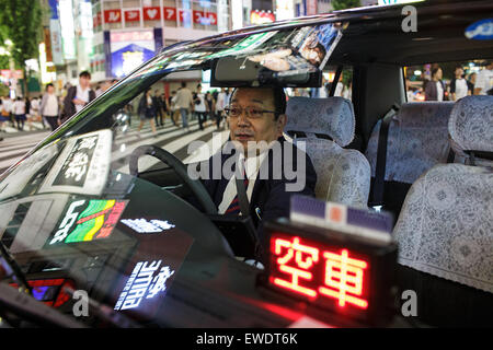 Un chauffeur de taxi à l'intérieur de sa voiture le soir à Shinjuku, Tokyo, Japon Banque D'Images