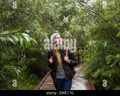 Souriante jeune femme marchant à travers la forêt dans un parc Banque D'Images