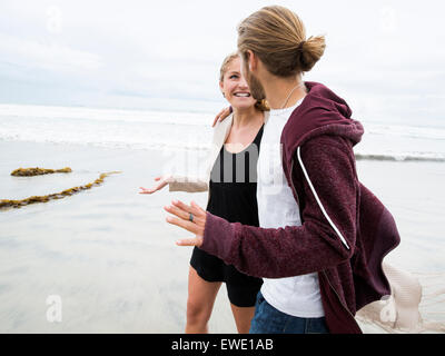 Jeune homme et jeune femme marche sur une plage, smiling Banque D'Images