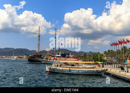 MUGLA, TURQUIE - juin 1, 2015 : les bateaux à voile et de personnes qui se promènent sur le littoral de port de plaisance de Marmaris, sous ciel nuageux. Banque D'Images