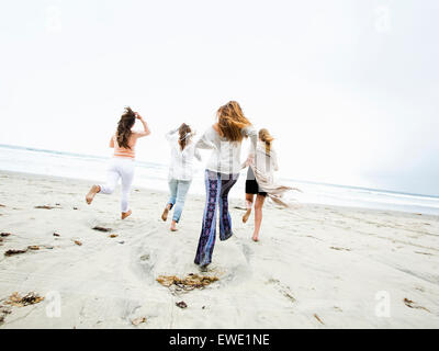 Un groupe de jeunes hommes et femmes s'exécutant sur une plage, s'amusant Banque D'Images