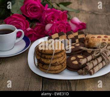 Rose fleurs, café et cookies différents sur une plaque Banque D'Images