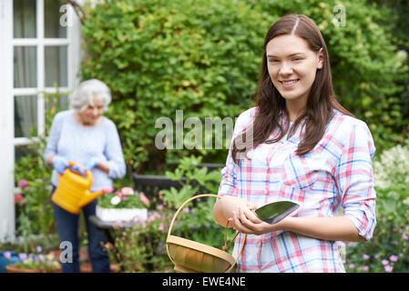 Teenage Granddaughter aider grand-mère à jardin Banque D'Images