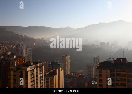 La Paz, Bolivie, 24 juin 2015. La fumée remplit les vallées du centre de la Paz peu après le lever du soleil après la nuit de San Juan. San Juan est traditionnellement considéré comme la période la plus froide de l'année et beaucoup de gens en Bolivie allument des feux de joie et déclenchent des feux d'artifice. Les autorités locales ont tenté de mettre fin à cette coutume au cours des dernières années pour réduire la pollution supplémentaire qu'elle provoque dans la ville, mais avec un succès limité. Cette vue donne vers l'est de Sopocachi au district de Miraflores et aux contreforts des Andes. Banque D'Images