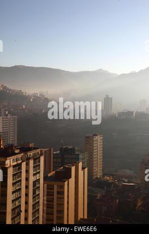 La Paz, Bolivie, 24 juin 2015. La fumée remplit les vallées du centre de la Paz peu après le lever du soleil après la nuit de San Juan. San Juan est traditionnellement considéré comme la période la plus froide de l'année et beaucoup de gens en Bolivie allument des feux de joie et déclenchent des feux d'artifice. Les autorités locales ont tenté de mettre fin à cette coutume au cours des dernières années pour réduire la pollution supplémentaire qu'elle provoque dans la ville, mais avec un succès limité. Cette vue donne vers l'est de Sopocachi au district de Miraflores et aux contreforts des Andes. Banque D'Images