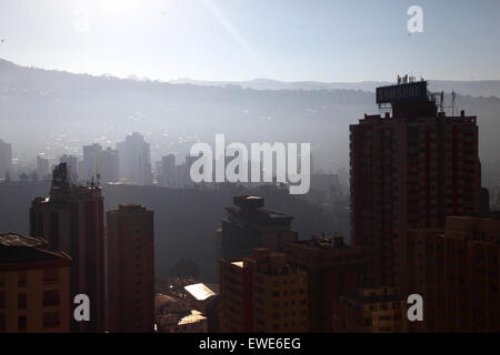 La Paz, Bolivie, 24 juin 2015. La fumée remplit les vallées du centre de la Paz peu après le lever du soleil après la nuit de San Juan. San Juan est traditionnellement considéré comme la période la plus froide de l'année et beaucoup de gens en Bolivie allument des feux de joie et déclenchent des feux d'artifice. Les autorités locales ont tenté de mettre fin à cette coutume ces dernières années pour réduire la pollution supplémentaire qu'elle cause dans la ville, mais avec un succès limité. Cette vue regarde à l'est de Sopocachi vers les districts de Miraflores et Pampahasi (sur la crête) et les contreforts des Andes. Banque D'Images