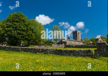 Église St Oswalds, Askrigg dans Wensleydale, vu plus d'une prairie de fleurs sauvages au début de l'été. Le Yorkshire, UK. Banque D'Images