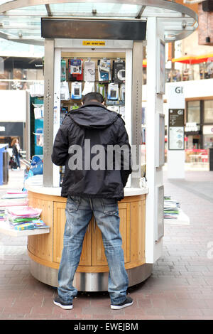 Vue arrière d'un homme vendant des accessoires de téléphone portable mobile à partir d'un panier dans un grand centre commercial à Bristol Banque D'Images