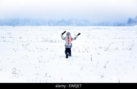 Petite fille s'enfuir sur le champ de neige Banque D'Images