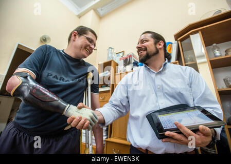 Stuzhenko Vasyl, qui a perdu son bras et une jambe lors de combats près de Illovaisk dans la région de Donetsk en août dernier, serre la main par sa main bionique à American prothésiste Chris Fantini pendant l'Ukraine aide prothétique Projet, projet de charité organisé par l'ukrainien et les travailleurs médicaux et les personnalités publiques pour transférer les connaissances et la réhabilitation prothétique de spécialistes américains et canadiens à leurs collègues en Ukraine. Au cours de projet cinq ukrainiens ont reçu une prothèse bionique de haute qualité, dont trois soldats ukrainiens ont perdu leurs membres dans les batailles. Kiev, Ukraine. Banque D'Images