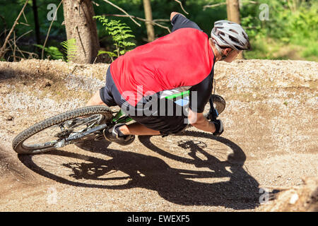 Mountain bike rider à travers pente gravité artificielle de chemin de terre. Banque D'Images