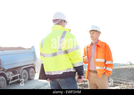 Ingénieurs discuter at construction site contre le ciel clair aux beaux jours Banque D'Images