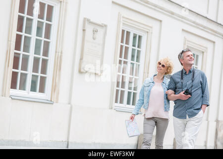 Happy middle-aged tourist couple walking arm in arm par la construction Banque D'Images