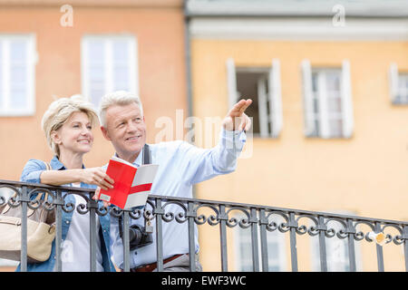 Homme heureux montrant quelque chose pour femme avec guide en ville Banque D'Images