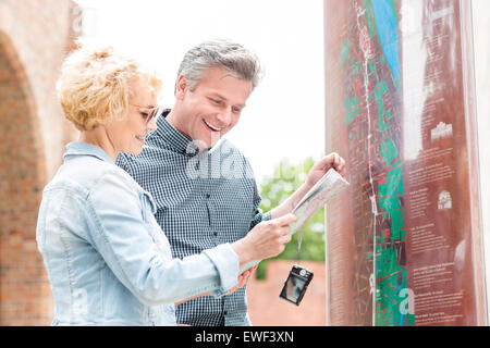 Cheerful couple reading map in city Banque D'Images